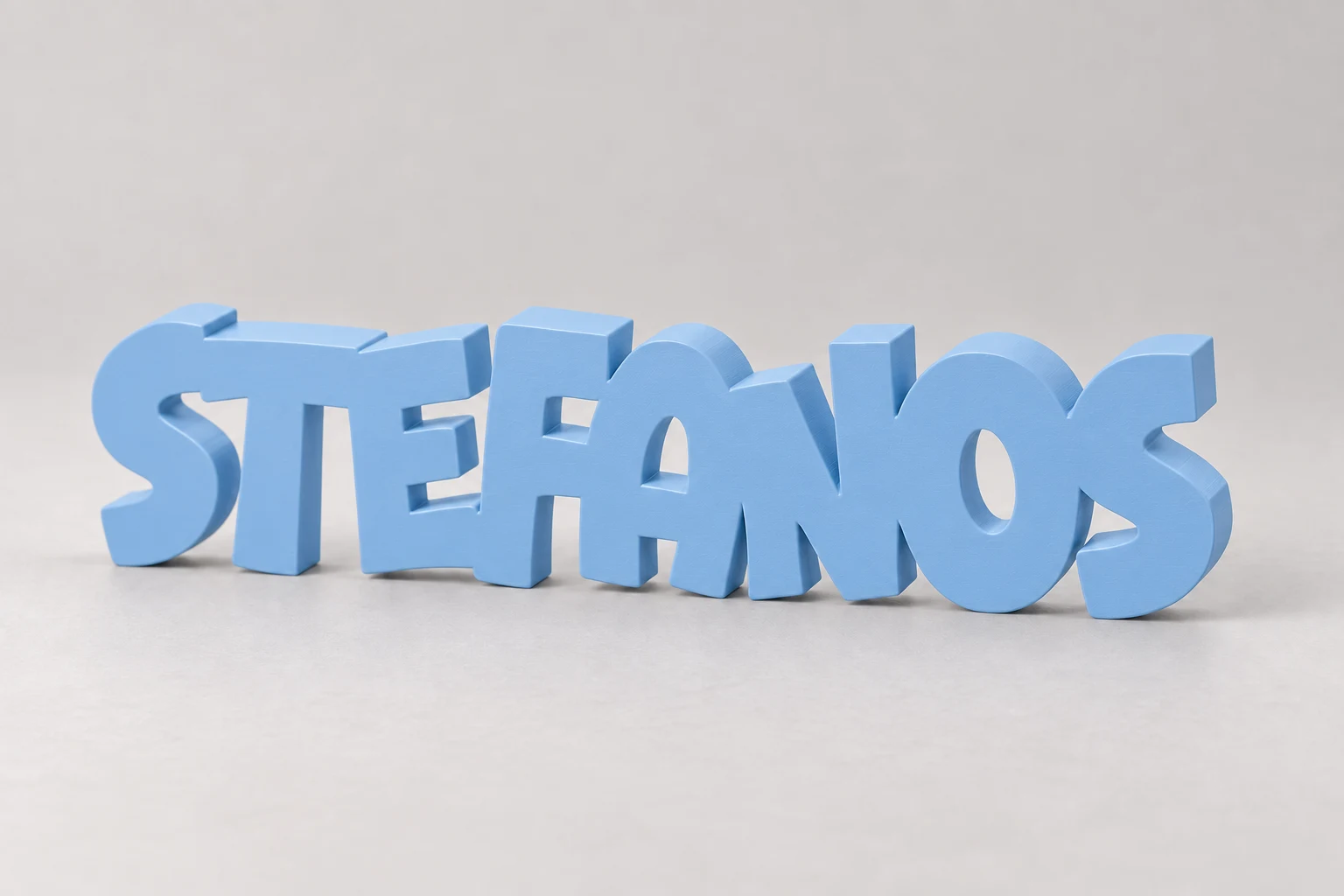 Baby-blue STEFANOS name decoration standing on a studio surface